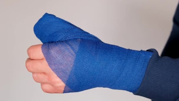 断了胳膊包扎手，外科敷料。白色背景上的手臂上的蓝色手术绷带。医学概念。骨折和扭伤绷带和绷带. — 图库视频影像