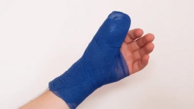 Bandajlı el. Kolunda beyaz bir arka planda mavi cerrahi bandaj var. Kırık kol. Kırıklar ve burkulmalar. Bandajlar ve bandajlar..