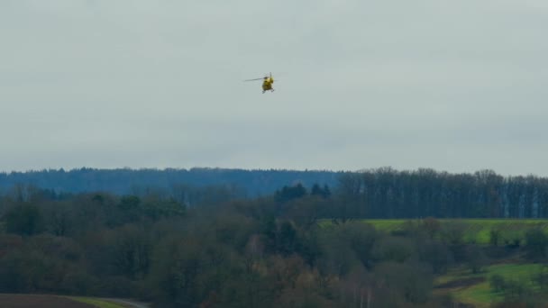 Hélicoptère. Transport aérien. Hélicoptère médical ambulancier. Un hélicoptère jaune prend le ciel au-dessus des montagnes et des champs. — Video