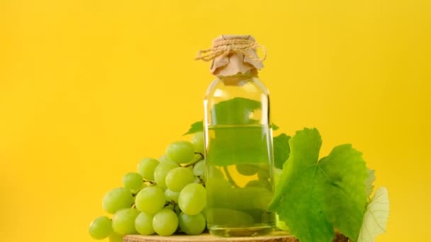 Aceite de semilla de uva. Botella y racimo de uvas verdes sobre un fondo amarillo brillante — Vídeos de Stock