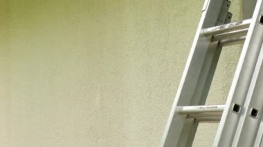 Duvar boyası. Ev tadilatı. İnşaat ve yenileme konsepti. Paten evin duvarlarını kum rengiyle boyuyor. Ev gri tonlarda boyanıyor. Dekoratör bir silindirle duvar boyuyor..