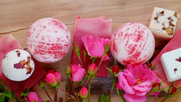 Банные бомбы, трюфели, мыло с экстрактом розы и бутоны роз на деревянном фоне — стоковое видео