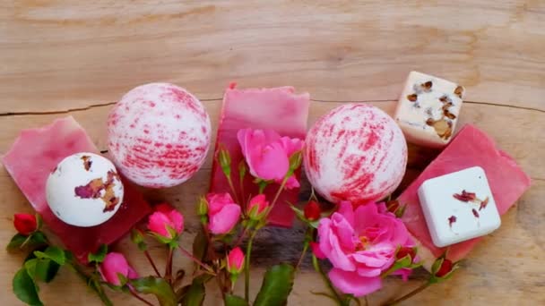 Цветочные ванны Бомбы, трюфели, мыло с экстрактом розы и бутоны роз на фоне деревянной доски. розовая косметика. Красота и ароматерапия. — стоковое видео