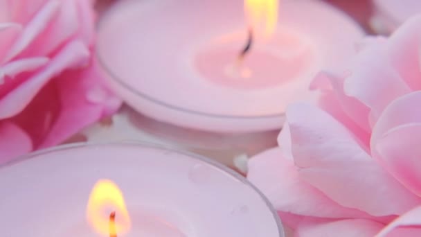 Velas encendidas y rosas rosadas en el agua. Velas de fondo.Velas de rosa.Aromaterapia y spa.Conjunto de velas ardientes. Llama de vela. — Vídeo de stock