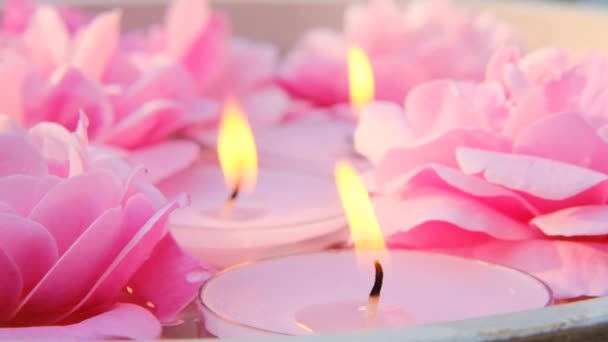 Rosenkerzen.Rosafarbene brennende Kerzen und rosa Rosen in Wasser.Aromatherapie und Wellnesskonzept.Kerzenflamme. Kerzen hintergrund.Brennende Kerzen — Stockvideo