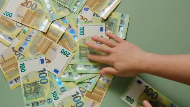 欧元现钞在绿色背景下，由女性手握。货币和金融。女性的手在绿色背景下算计着欧元的钞票。. — 图库视频影像