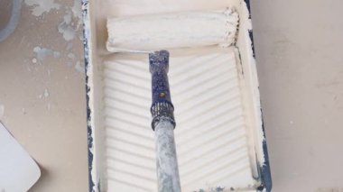 Patenli ve boyalı. Bej boyalı bir konteynırda yapım rulosu. Duvar boyası ve yenileme. Bej renkte ev boyası..