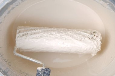 Bej tonlarda boya. Paten ve boya. Bej boyalı bir kovada inşaat rulosu. Bej renkte boya. Duvar boyası ve yenileme. 