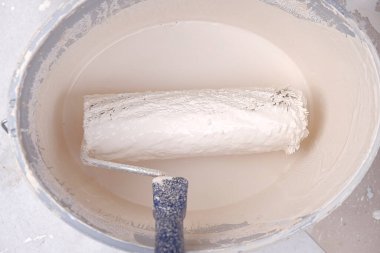 Paten ve boya. Bej boyalı bir kovada inşaat rulosu. Bej tonlarda ev boyası.