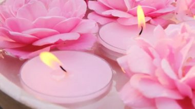 Gül mumları, romaterapi ve spa. Pembe yanan mumlar ve suda pembe güller. Mum alevi. Mumlar arka planda. Mumlar yanıyor.