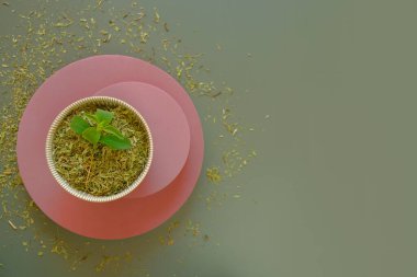 Stevia rebaudiana.Stevioside Sweetener . Yeşil arka planda pembe kaidede duran fincanda kurumuş ve taze yeşil bir stevia. Stevioside Sweetener. Doğal düşük kalori tatlandırıcı 