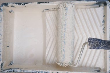 Duvar boyası ve yenileme. Paten ve boya. Bej boyalı bir konteynırda rulo.