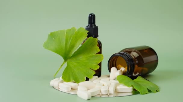 Ginkgo biloba .Green ginkgo biloba leaf, white tablets and liquid ginkgo biloba extract in brown glass jar on green background.Preparations with ginkgo biloba extract — 비디오