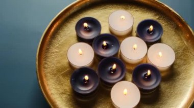 Koyu mavi arka planda altın tepside mum yakmak. Döndürme. Zen ve rahatlama kavramı. Büyü ve esrarengiz..