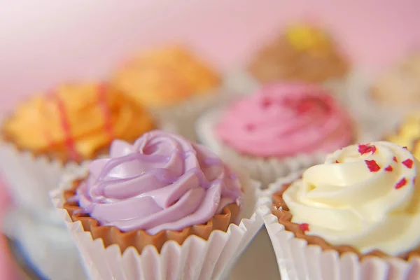 クリームカップケーキピンクの背景にケーキ。甘いテーブルを並べ替え。スイーツとデザート。焼き菓子 — ストック写真