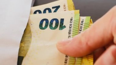 Zarfta para var. Siyah zemin üzerinde beyaz bir zarf içinde Euro banknotları. El zarftan para çekiyor.