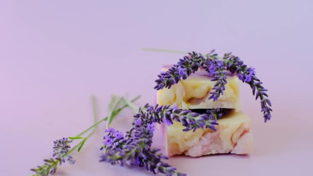 Seife mit Lavendelextrakt. Riegel lila Seife und Lavendelblüten auf violettem Hintergrund. Aromatherapie und Wellness mit Lavendelduft. — Stockvideo