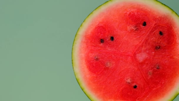 Wassermelonenhälfte auf grünem Hintergrund. Rotation.Wassermelonenfruchtfleisch aus nächster Nähe. Frische reife rote Wassermelone auf halbe.Appetitliche Sommerfrüchte. — Stockvideo