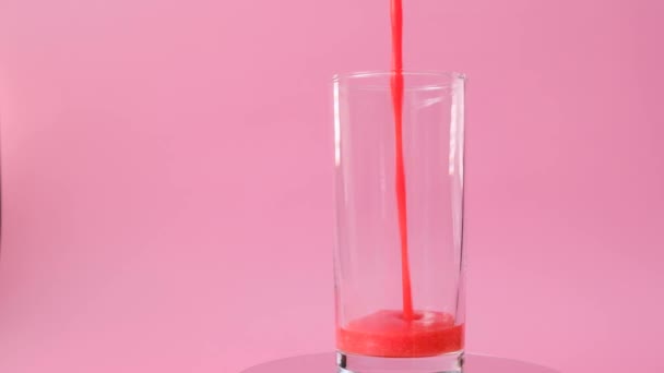 Erdbeer-Smoothies. Pinkfarbener Cocktail in einem transparenten Glasbecher auf rosa Hintergrund. Rotation.Sommercocktails und Getränke.Köstliches und gesundes Getränk aus Sommerbeeren und Milch — Stockvideo