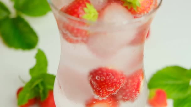 Eau minérale aux fraises dans un gobelet en verre. Cocktail d'été rafraîchissant. Boissons estivales. — Video
