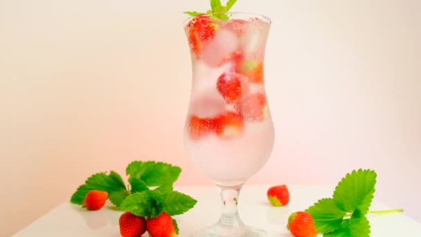 Jordgubbsdryck. is i ett glas med en cocktail.slow motion. mineralvatten med is och jordgubbar. Uppfriskande sommarcocktail.Sommardrycker — Stockvideo