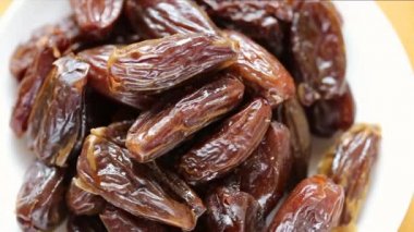 Kuru tarihler beyaz bir tabakta yakın plan. Kuru tarihler yığını. Tatlı meyve tatlısı