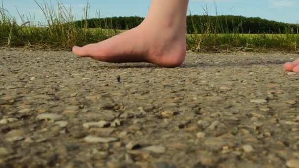 Niño camina hacia la distancia.cámara lenta. Los pies desnudos de los niños caminan en el camino a. Temporada de verano.Humor de verano. — Vídeos de Stock