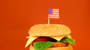 Amerika Birleşik Devletleri 'nde Hamburger Günü. Kahverengi bir arka planda dekoratif Amerikan bayrağı olan hamburger.