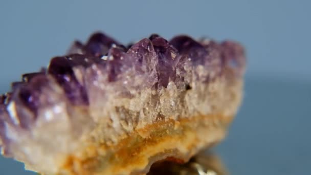 Ametiststen. Ametist lila kristall närbild på en blå bakgrund. Textur av ametist druse närbild.Rotation. — Stockvideo