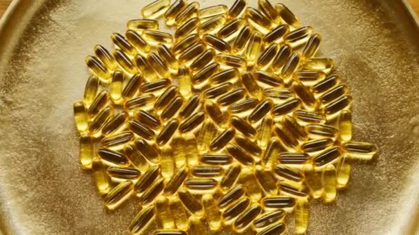 Fish Oil Gelatin Cápsulas sobre um fundo de ouro.Suplementos naturais e vitaminas.Alimentação saudável — Vídeo de Stock