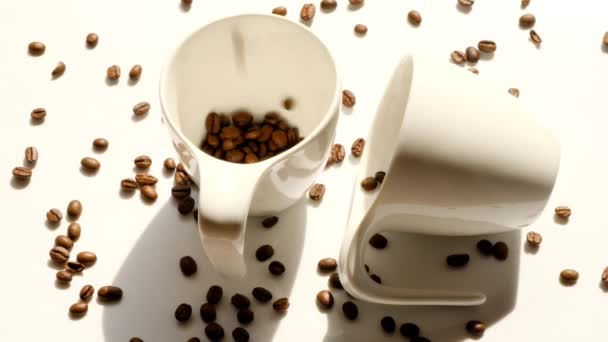 Café em copos brancos e grãos de café caindo. bebida da manhã — Vídeo de Stock