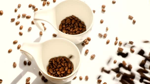 Café en tazas blancas. Granos de café en tazas de cerámica y granos de café que caen. — Vídeo de stock