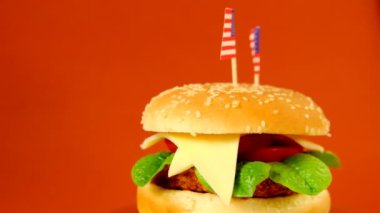 Hamburger. Fast food. Amerika Birleşik Devletleri 'nde Hamburger Günü. Kahverengi bir arka planda dekoratif Amerikan bayrağı olan hamburger.