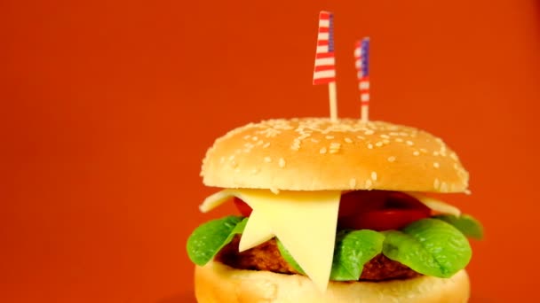 Hamburguesa. comida rápida.Hamburger Day in the United States of America. Hamburguesa con bandera americana decorativa en un fondo marrón. — Vídeo de stock