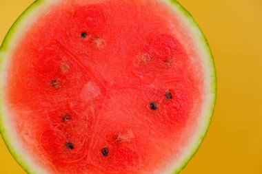 Karpuz posasını yakından çek. Sarı arka planda karpuz kesiği. Olgun kırmızı karpuz yarısı. İştah açıcı yaz meyveleri.