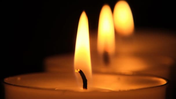 Świece zbliżenie ustawione na czarnym tle.Płomień świecy. Płonące świece w ciemności — Wideo stockowe