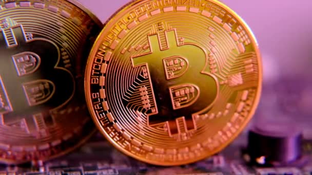 Bitcoin. Blockchain cryptocurrency.Gold en zilver Bitcoin munten in paars licht op computer moederbord.cryptogeld investeren concept — Stockvideo