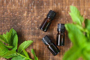 Nanenin esaslı yağı. Cam şişe ve ahşap zemin üzerinde nane şekeri. Romaterapi ve organik doğal kozmetik..