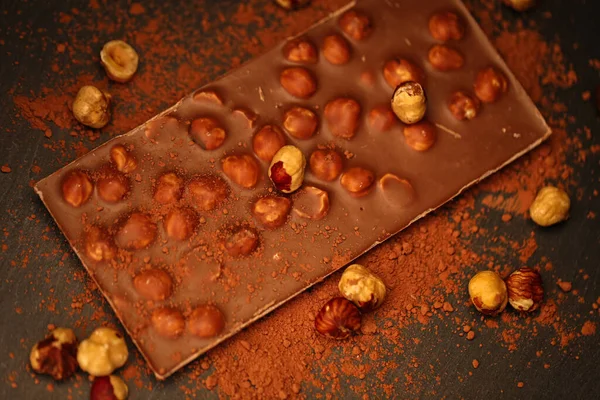 Schokoladenbar.Schokolade mit Haselnüssen und Kakaopulver auf Schiefergrund. Schokoladendessert mit Nüssen. Tafel Schokolade. Desserts und Süßigkeiten — Stockfoto