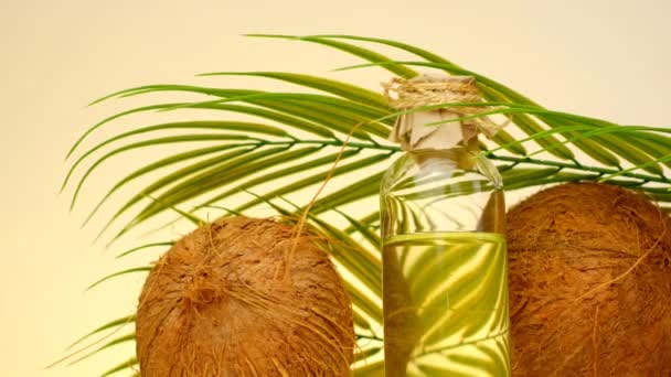Aceite de coco en botellas y cocos sobre fondo amarillo.Aceite de coco ecológico. — Vídeo de stock