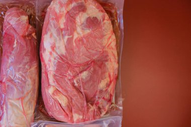 Boşluktaki bir parça et. Burgundy arka planında et ve domuz yağı vakumlu poşetlerde. Protein besin. Çiftlik organik eti