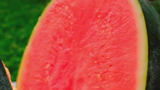 Vattenmelon i ett snitt i händerna i en sommarträdgård.slow motion.Färsk mogen röd vattenmelon hälften. Vattenmelonmassa närbild.Aptitretare sommarfrukter. — Stockvideo