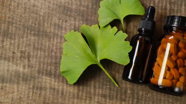 Ginkgo biloba pilulky.Alternativní medicína a homeopatie.Ginkgo biloba tablety a tekuté ginkgo extract.Brown sklenice s pilulkami, ginkgo biloba listy a tekutý extrakt — Stock video