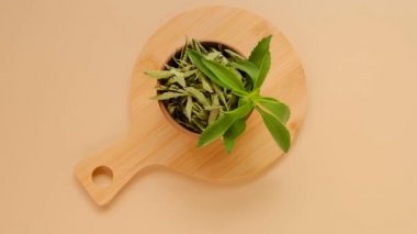 Stevia yuvarlak kaselerde kuru stevia ile birlikte bej bir arka planda yuvarlak tahta bir tahta üzerinde ayrılır. Yukarıdan bak. Organik doğal tatlılık. Stevia bitkisi..