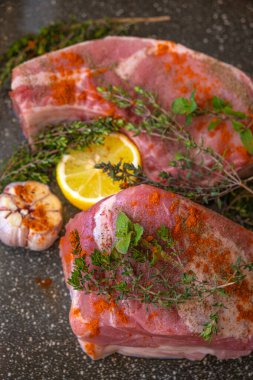 Baharatlı ve otlu domuz eti. Çiğ et parçaları, kekik, kırmızı biber tozu, arkaplanda limon ve sarımsak. Et ürünleri. Protein besin.. 