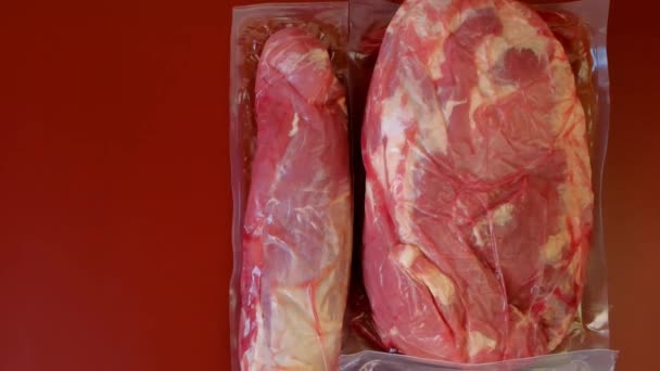 Kött och fläsk fett i vakuumpåsar på vinrött bakgrund. Proteinnäring. Köttprodukter. Rött kött på en röd bakgrund.Rått färskt kött närbild — Stockvideo