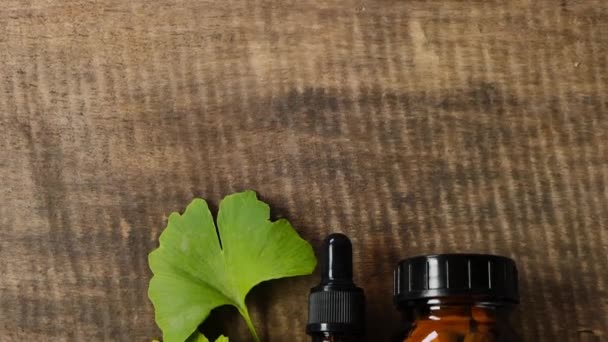 Ginkgo biloba tabletter och flytande ginkgo extrakt. glasburk med piller, ginkgo biloba blad och flytande extrakt på trä bakgrund.Ginkgo biloba piller.Alternativ medicin och homeopati. — Stockvideo