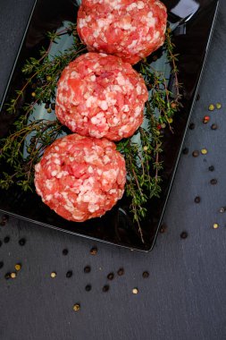 Çiğ kıymalı domuz eti. Köfteler yakın plan. Kıymalı köfteler, siyah bir arka planda kekik filizi ile dizilmiş. Et ürünleri. Çiftlik organik eti..
