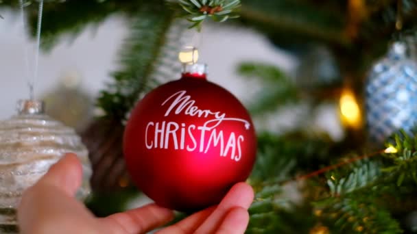 Boldog karácsonyt.Vörös karácsonyi labda közelkép karácsonyfa fényes koszorúval.Téli ünnepek. — Stock videók