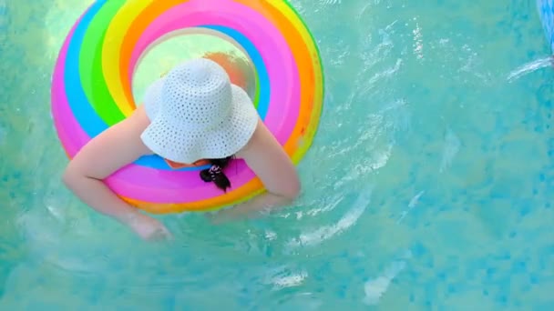 Fille avec un anneau gonflable arc-en-ciel dans la piscine.ralenti. L'enfant nage dans la piscine.Heure d'été et vacances. — Video